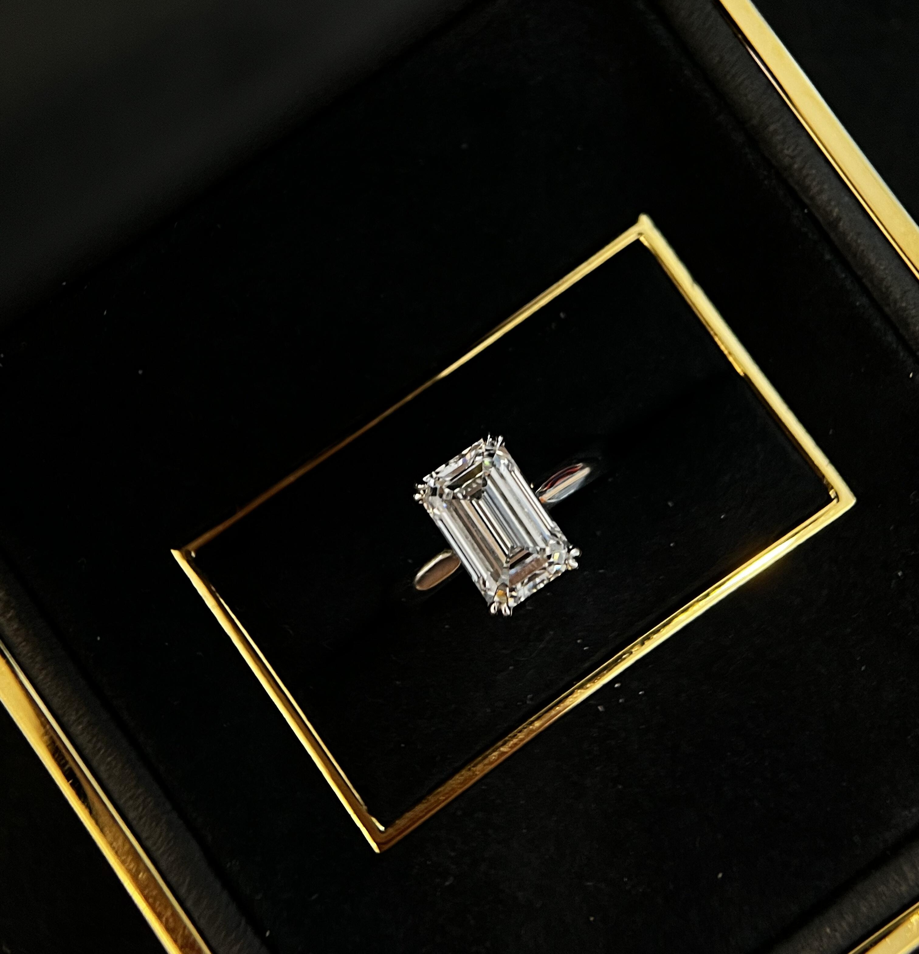 Minimal emerald-cut solitaire in platinum on velvet ring tray